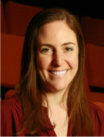 Headshot of woman with light brown hair below her shoulders smiles. She wears a maroon shirt matching the background color.